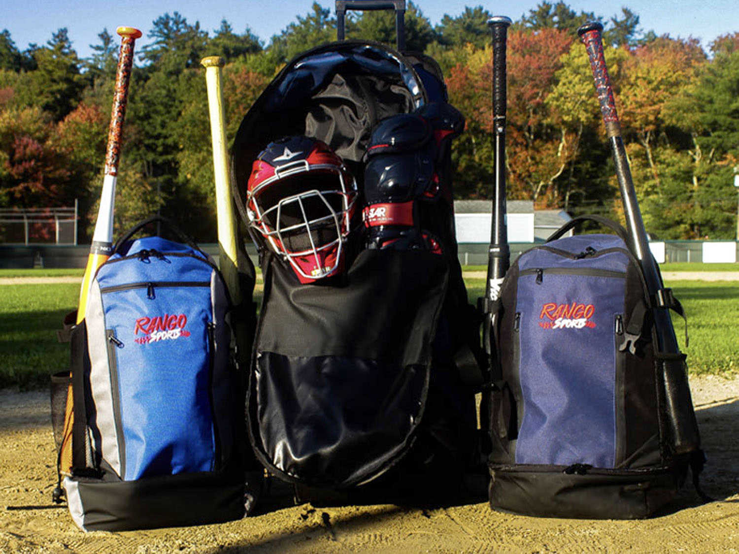 Rango Sports custom Walrus-Pack baseball bags and rolling Clubhouse bag displayed on a field with bats, helmet, and catcher’s gear.